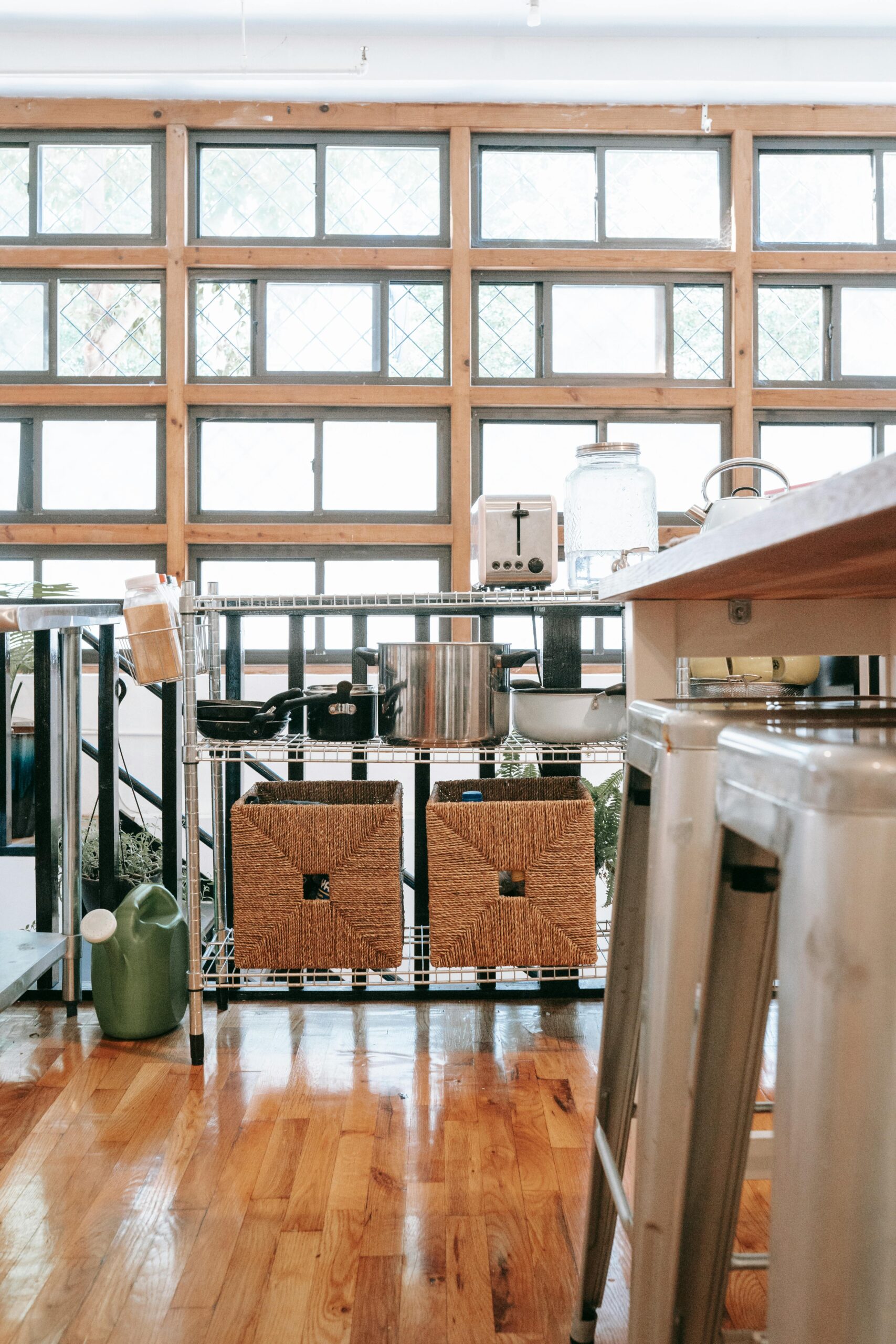 Contemporary kitchen with natural light, sleek metal shelving, and wooden flooring.